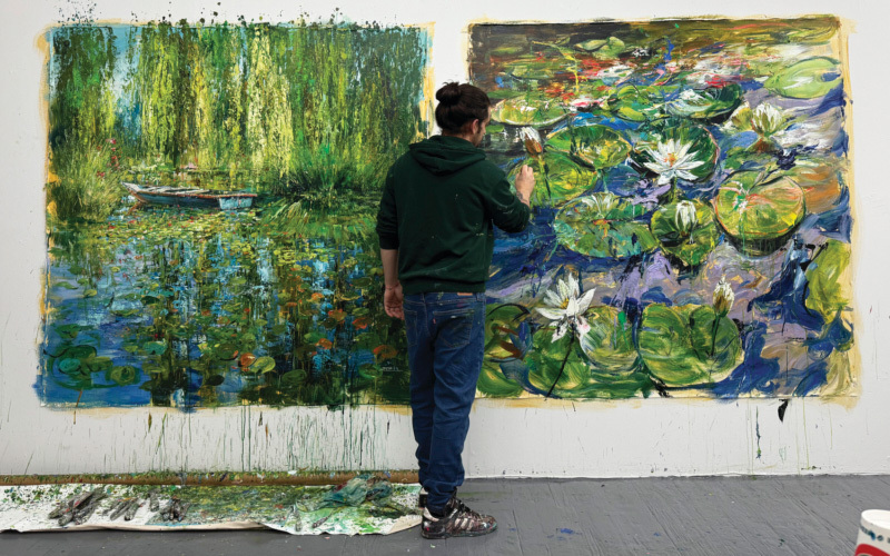 A male painter painting a large green painting